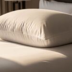 Luxurious white goose down pillow fluffed on hotel-style bed with soft morning light