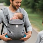 Parent demonstrating front inward carry with newborn in breathable 6-in-1 baby carrier during a family walk