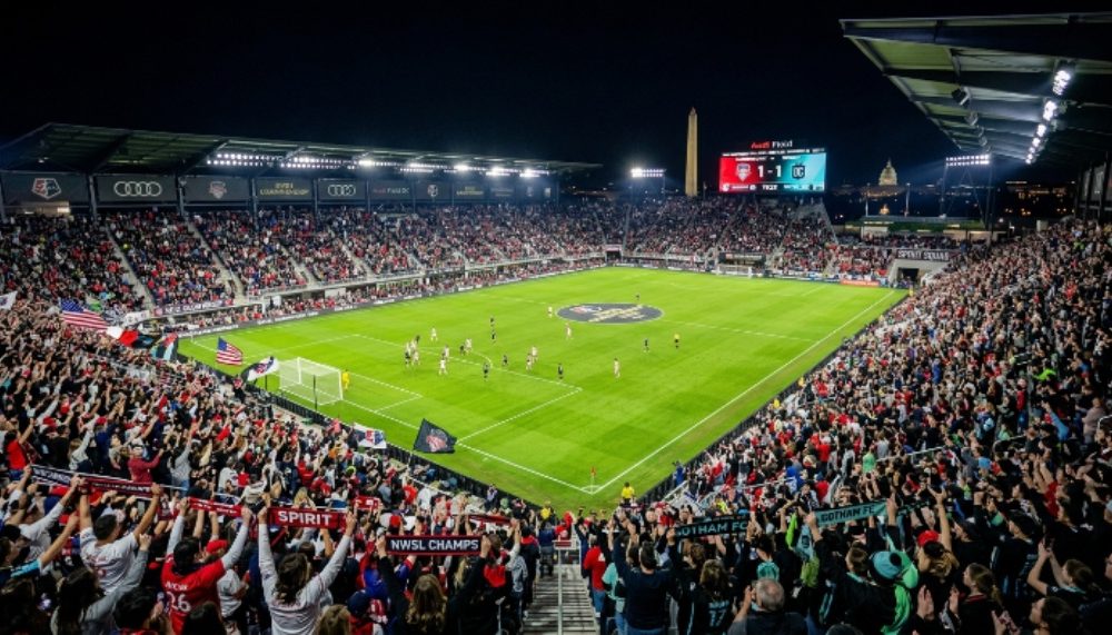 Thousands of soccer fans filling Audi Field in Washington DC for the 2026 NWSL Championship on November 21 under stadium lights at night